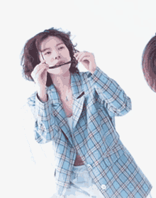 a woman wearing sunglasses and a plaid jacket with korean writing behind her