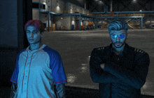 two men standing next to each other with their arms crossed in front of a warehouse