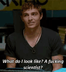 a man is sitting in front of a sign that says what do i look like ? a fucking scientist ?