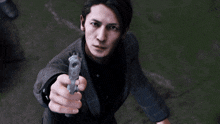 a man in a suit is pointing a gun at the camera with flames coming out of it