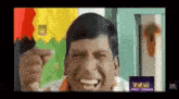 a man is making a funny face in front of a colorful background .