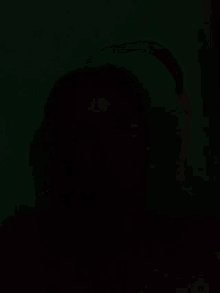 a man without a shirt is laying down in the dark with his eyes closed .