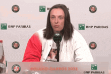 a woman is sitting at a table with a bnp paribas sign behind her