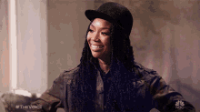 a woman wearing a hat and a jacket with nbc written on the bottom