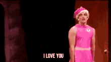 a man dressed as a woman in a pink dress and hat is saying `` i love you '' .