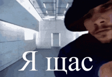 a man in a black hat is standing in a hallway with the word a on the bottom