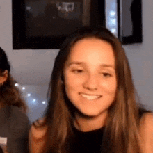 a young woman with long hair is smiling and looking at the camera in a living room .