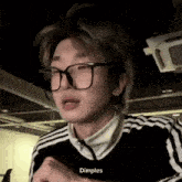 a young man wearing glasses and a black and white striped jacket .