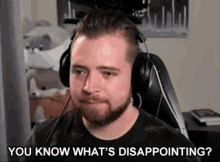 a man with a beard wearing headphones is sitting in front of a computer screen .