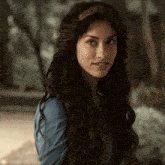 a woman wearing a blue shirt and a headband looks at the camera