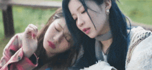 two girls with blue hair are laying on a bench with their eyes closed .
