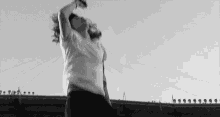 a black and white photo of a man standing on top of a roof holding a microphone .