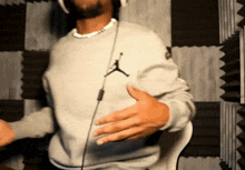 a man wearing headphones and a grey sweater with a jordan logo on it