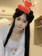 a woman with a red heart on her head looks at the camera