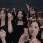 a group of young women are standing next to each other with their hands in the air and smiling .