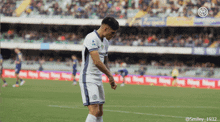 a soccer player stands on a field with a smiley 1932 logo in the background