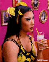 a woman wearing a banana headband is holding a glass of water with a straw .
