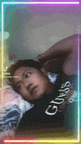 a man wearing a guess los angeles shirt is laying in bed