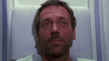 a man with a beard and blue eyes is laying down