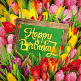 a bunch of flowers with a green sign that says " happy birthday "