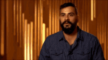 a man with a beard is standing in front of a wall