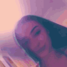 a close up of a woman 's face in a blurry photo with a pink background .