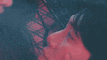 a close up of a person 's face in a dark room with a red background .