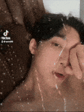 a young man is laying in a bathtub with water coming out of the window .