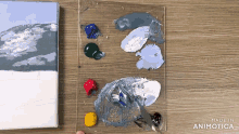 a painting is being painted on a canvas next to a paint palette