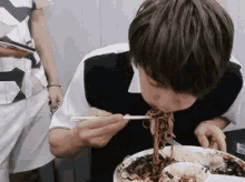 a young man is eating noodles with chopsticks .