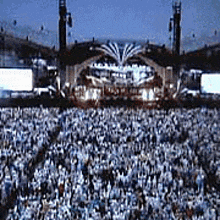 a large crowd of people are gathered in front of a stage at a concert