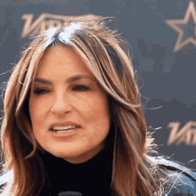 a woman is speaking into a microphone in front of a wall that says variety