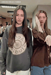 two women standing next to each other with one wearing a sweatshirt that says " out "