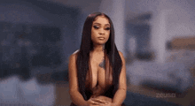a naked woman with long hair and a tattoo on her chest is sitting down .