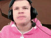 a man wearing headphones and a pink hoodie is looking at the camera .