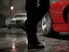 a person is walking in front of a red car