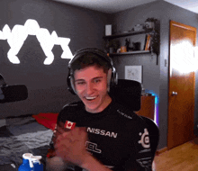 a man wearing headphones and a nissan shirt smiles
