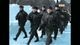 a group of soldiers marching in the snow with the letters tht on the bottom right