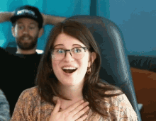 a woman wearing glasses and hoop earrings is laughing