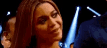 a close up of a woman 's face in a dark room with blue lights behind her .