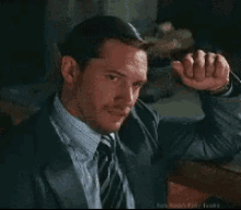 a man in a suit and tie is covering his mouth with his hands