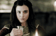 a woman is holding a small cup in her hand