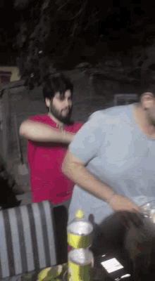 a man in a red shirt and a man in a blue shirt are standing next to each other