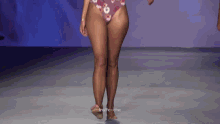 a woman in a bikini walks down a runway with the word poemas in the background