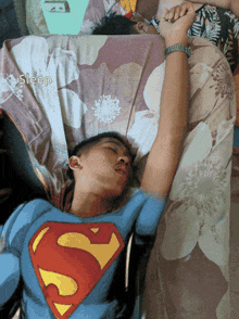 a man wearing a superman shirt is sleeping in bed