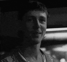 a black and white photo of a man wearing a necklace .
