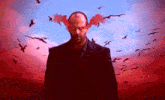 a man in a suit and tie stands in front of a flock of birds