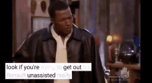 a man in a leather jacket is standing in a room talking to another man .