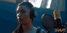 a woman wearing headphones stands in front of a microphone with the word bravas on the bottom right