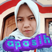 a woman wearing a white hijab is standing in front of a door with the word apasih displayed in front of her